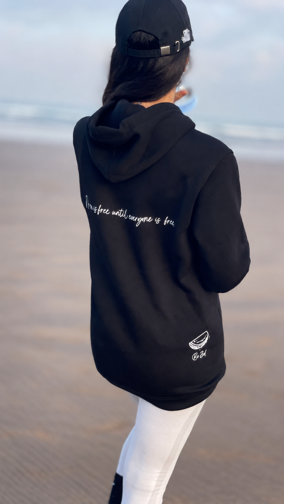 Le sweat #FreeP porté de dos à la plage, avec son inscription et sa signature Be Zed